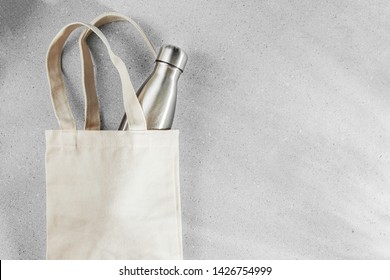 Natural color eco bag with reusable metal water bottle. Zero waste concept. Plastic free. Flat lay, top view