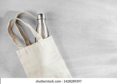 Natural color eco bag with reusable metal water bottle. Zero waste concept. Plastic free. Flat lay, top view