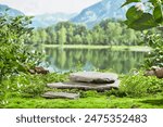 Natural concept photography from front angle, against the clear green lake and mountain landscape background. A high podium displayed in center of lawn, made by two flat stones stacked on each other