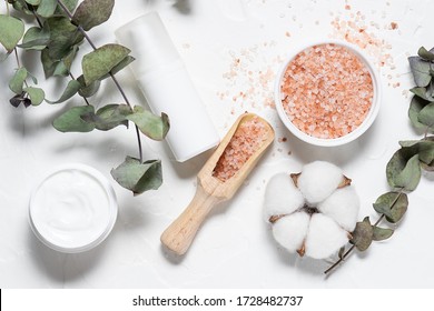 Natural cosmetic products for bath and skin care with eucalyptus twigs and cotton flowers on white background top view. Spa and wellness concept.