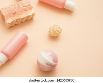 Natural Cosmetic Products. Flat Lay Of Handmade Soap, Diy Bath Bomb And Lotion Bottles Over Peach Color Background. Copy Space.