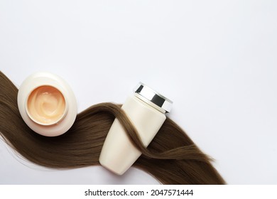 Natural cosmetic products and hair lock on white background, flat lay. Space for text