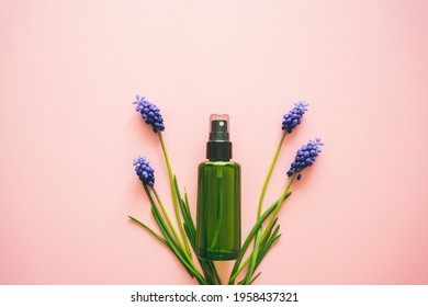 Natural Cosmetics In A Green Bottle And Blue Flowers On A Pink Background. Spring, Body Care, Spa, Flat Lay. 