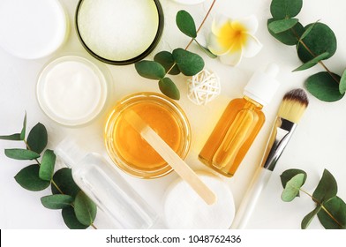 Naturkosmetische Inhaltsstoffe für Hautpflege, Körperpflege und Haarpflege. Goldener Honig in Glas und grüne pflanzliche Eukalyptusblätter. Flaschen mit Draufsicht, weißer Hintergrund