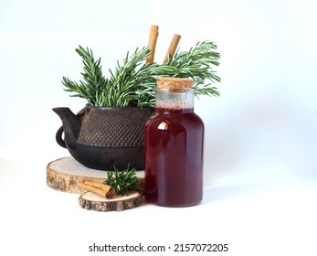 Natural cosmetics from rosemary and cinnamon. Hair tonic in a glass bottle. Wooden saw cuts, rosemary branches and cinnamon sticks. Vintage teapot in the background.