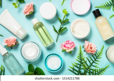 Natural Cosmetics, Skin Care Product - Cream, Lotion, Soap On Blue Background With Green Leaves And Flowers. Flat Lay Image With Copy Space.