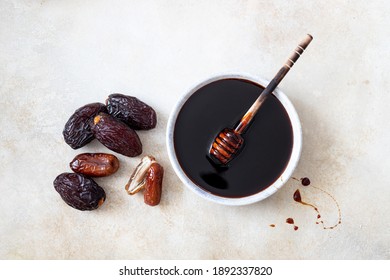 Natural date syrup in a bowl with whole dates in the background - Shutterstock ID 1892337820