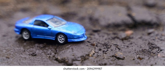 Natural Disasters. A Blue Car Drives Along A Road Destroyed By A Landslide.