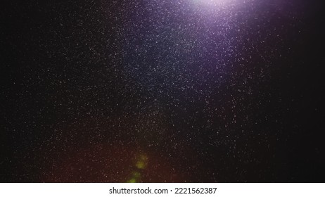 Natural dust particles floating on black background with light. Glittering particles in the air with effect bokeh. Macro shot of texture whites snow, smoke, steam, fog with purple glare luminosity. - Shutterstock ID 2221562387