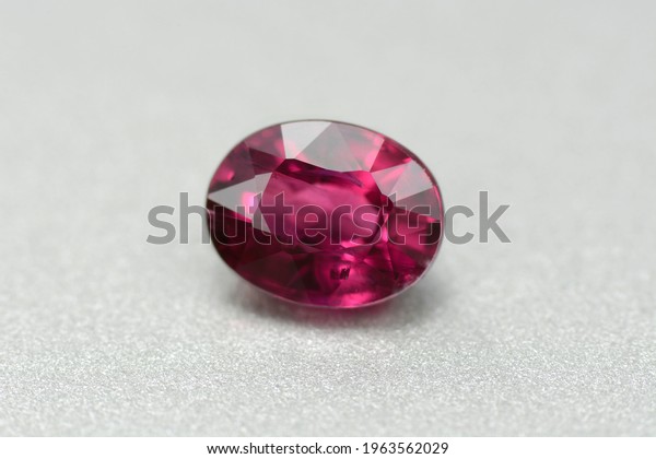 Natural earth mined unheated untreated oval\
faceted red color ruby gemstone from Winza, Tanzania. Visible\
unclusions, micro crack. Closeup front photo on gray pattern\
background. Gemology\
theme.
