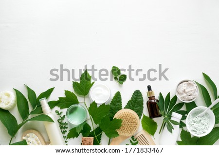 Natural eco beauty. Cosmetic products and green leaves on white background, top view, copy space. Natural organic skincare, spa, healthy lifestyle concept.