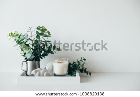 Natural eco home decor with green leaves and burning candle on t