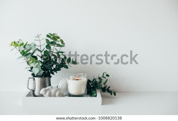 Natural eco home decor with green leaves and burning\
candle on t