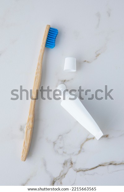 Natural eco-friendly bamboo brush with white\
bristles and tube of\
toothpaste.