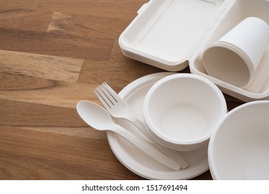 Natural eco-friendly disposable utensils (fork, spoon, dish plate, bowl, cup and fast food box container) made of fiber of bagasse and bamboo on wooden table background with copy space. Save the earth