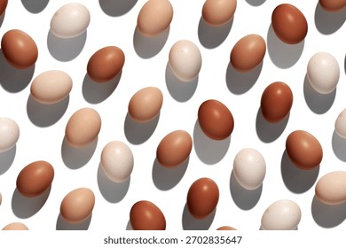 Natural eggs repeat pattern, beige brown colored Chicken egg with shadow at sunlight isolated on white background. Minimal Easter holiday concept, top view food still life photo, trend patterns