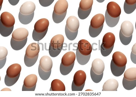 Natural eggs repeat pattern, beige brown colored Chicken egg with shadow at sunlight isolated on white background. Minimal Easter holiday concept, top view food still life photo, trend patterns