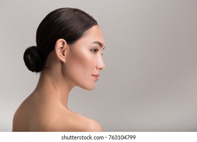 Natural female beauty concept. Side view profile of gorgeous exotic young naked woman is looking ahead thoughtfully. Isolated background with copy space in the right side