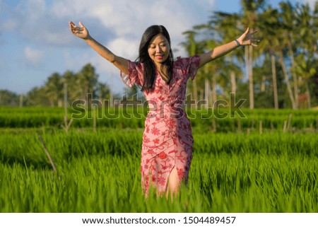 natural and fresh lifestyle portrait of  young beautiful and attractive Asian Korean woman in elegant dress walking on green rice field enjoying exotic Summer holidays trip in nature 