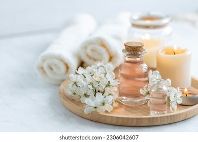 Natural fresh perfume with the scent of apple tree blooming flower on wooden bamboo tray. Aromatherapy, wellness, luxury perfumery concept. Organic ingredients for toilet water and essential oils