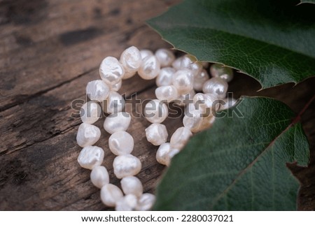 Natural freshwater pearls of various shapes and colors are photographed on a wooden board 
