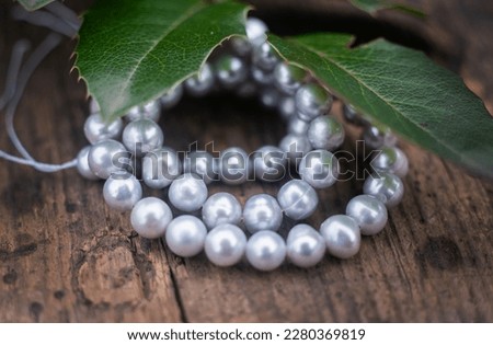 Natural freshwater pearls of various shapes and colors are photographed on a wooden board 