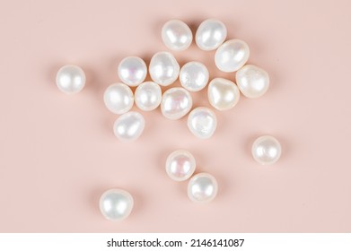 Natural freshwater round pearl beads on pink background. Top view.