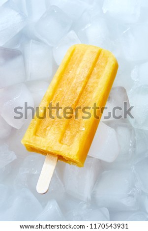 Natural frozen peach smoothies on a stick on ice cubes. Dietary cold dessert. Top view