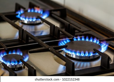 Natural Gas Burning On Kitchen Gas Stove In The Dark. Panel From Steel With A Gas Ring Burner On A Black Background, Close-up Shooting.