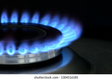 Natural Gas Burning On Kitchen Gas Stove. Panel From Steel With A Gas Ring Burner On A Black Background, Macro Shooting