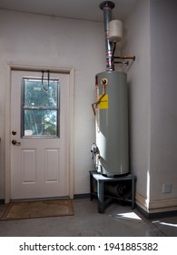 Natural Gas Hot Water Heater Tank With Copper Pipe Plumbing In Residential Garage.