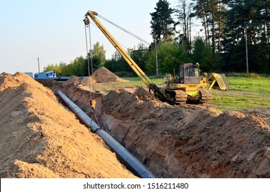 Natural Gas Pipeline Construction Work. A Dug Trench In The Ground For The Installation And Installation Of Industrial Gas And Oil Pipes. Crawler Crane Bulldozer With Side Boom Or Pipelayer 