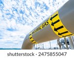 Natural gas pipeline with high pressure and direction sign at compressor station. Concept of energy transportation infrastructure