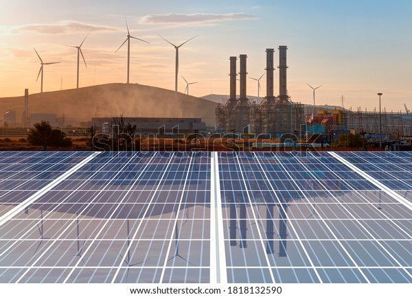 Natural gas processing plant with Renewable\
energy wind turbines generating electricity reflection to solar\
panels at sunset - Industrial concept\
