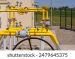 Natural gas pumping station among the spring fields. Yellow pipes, pressure gauges and valves - elements of the natural gas transmission installation . 