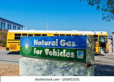 Natural Gas School Bus Fueling Behind Natural Gas For Vehicles Sign At Compressed Natural Gas CNG Fueling Station By PG&E, Pacific Gas And Electric Company - San Carlos, CA, USA - 2019