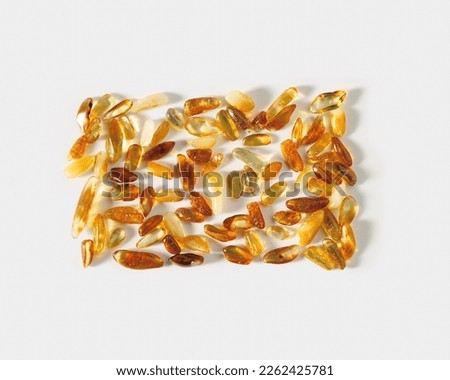 Natural gemstone amber stones at sunlight, yellow orange gradient color on light white background. Natural mineral for jewelry. Aesthetic lifestyle Amber gems, flatlay pattern, pieces ancient resin