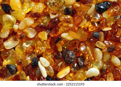 Natural gemstone amber texture background, small stones yellow orange gradient color. Natural mineral material for jewelry. Top view Amber texture. Aesthetic sunstones wallpaper, pieces ancient resin.