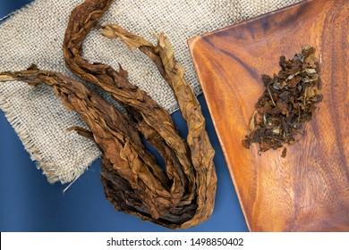 Natural Golden Tobacco Leaves On Burlap Background. Tobacco Whole And Loose Leaf Top View Photo. Rustic Raw Material For Cigarettes And Cigars. Smoking Tobacco Leaf. Aromatic Plant Dry And Grinded