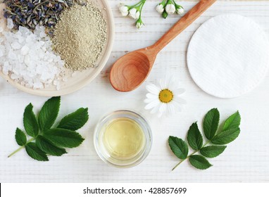 Natural herbal skin care products, top view ingredients. Cosmetic oil, clay, sea salt, herbs, plant leaves. Facial treatment preparation background. 