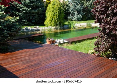 Natural home garden backyard with little pool lake, trees, plants and wooden decks, Ipe and cumaru decking - Shutterstock ID 2106639416