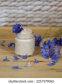                   Natural homemade eye cream with cornflowers (Centaurea cyanus) on the beige, white, blurred background.              - Shutterstock ID 2257379065