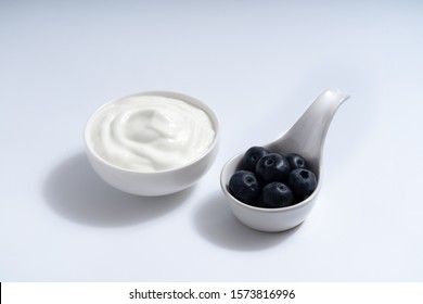 Natural Homemade Plain Organic Yogurt Mixed With Fresh Blueberry Fruit In White Bowl On White Background, Copy Space