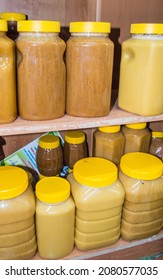 Natural honey in various jars on a wooden shelf, souvenir village market.