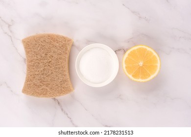 Natural Household Cleaning Bundle With Eco Ingredients - Walnut Dishcloth, Lemon, Baking Soda Or Citric Acid Over Marble Countertop Table Background. Green Cleaning Concept, Selective Focus