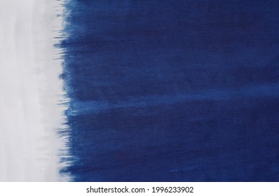 A natural indigo dye on white cotton fabric. Showing color flow and its pattern.  Good for texts, copy space, advertisement. Material, object, background, design categories.  