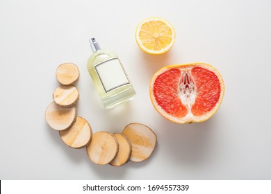Natural Ingredients For A Woody Citrus Fragrance, A Bottle Of Oil Or Perfume On A Background Of Grapefruit, Lemon And Wood. The Concept Of Perfumes And Aromatherapy, Body Care, Natural Oils.