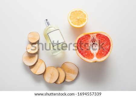 Natural ingredients for a woody citrus fragrance, a bottle of oil or perfume on a background of grapefruit, lemon and wood. The concept of perfumes and aromatherapy, body care, natural oils.