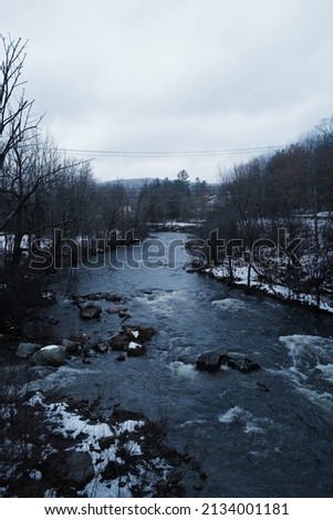 Natural landscape of roadside view and rocky river stream covered with snow