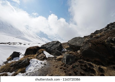 Natural Landscape Of Rocky Trail Steps With Snowy Mountain Cliff And Cloudy Blue Sky